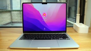 Bästa tunna laptops: En MacBook Air M2 står öppnad på ett träfärgat skrivbord med inloggningsskärmen aktiv.