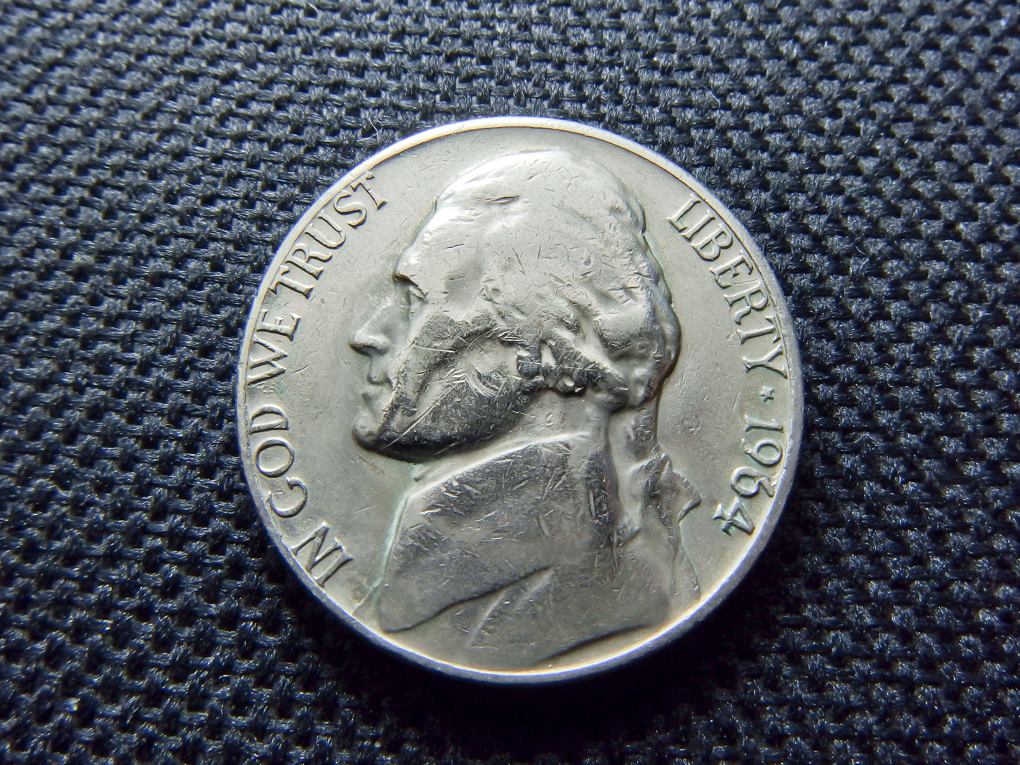 the face of a U.S. nickel coin on a black textured background