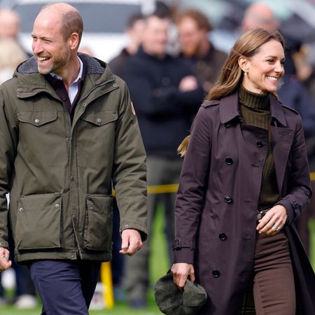 Prince William and Princess Kate walking next to each other and smiling in fall outfits