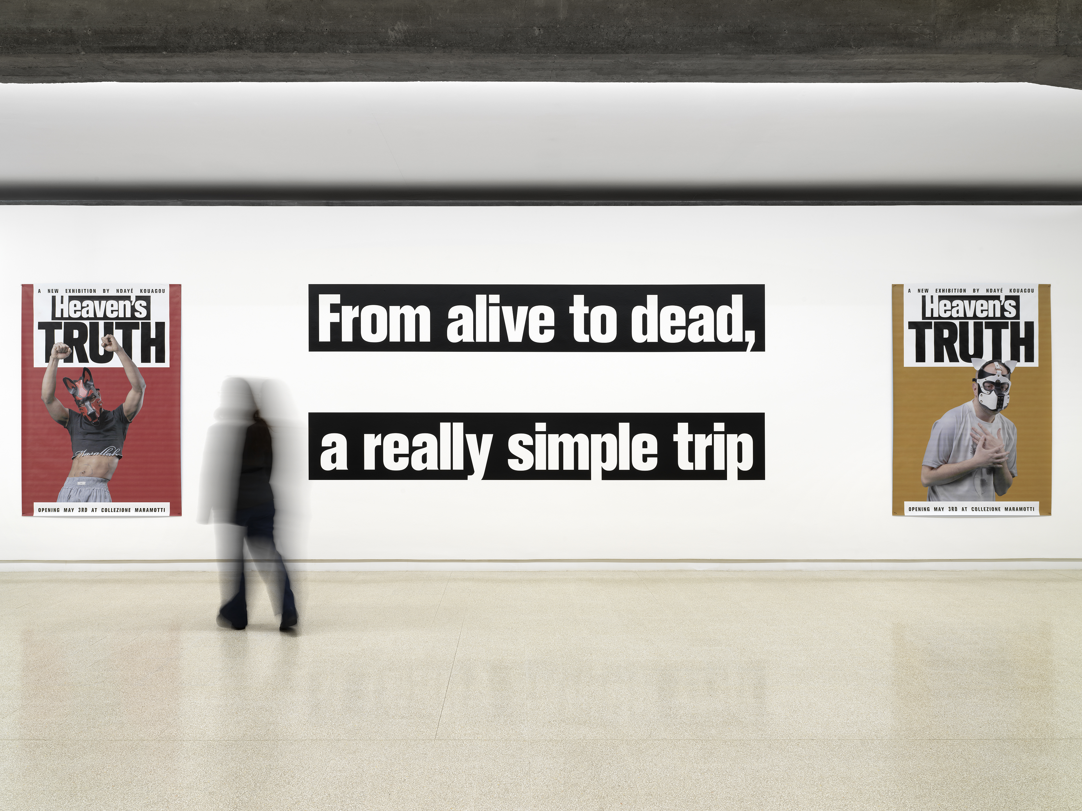 A white gallery space with two tabloid-style Heaven's Truth exhibition posters flanking a large wall text reading &amp;quot;From alive to dead, a really simple trip,&amp;quot; with a blurred figure walking past.