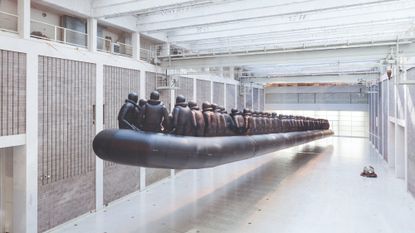 Metal artwork by Ai Weiwei of an enormous lifeboat with lots of people in lifejackets on board