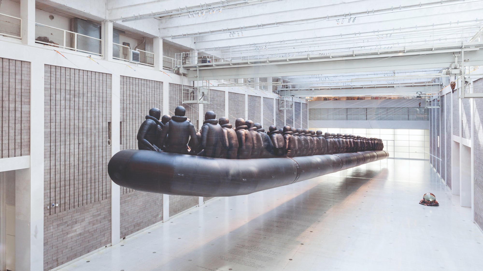 Metal artwork by Ai Weiwei of an enormous lifeboat with lots of people in lifejackets on board