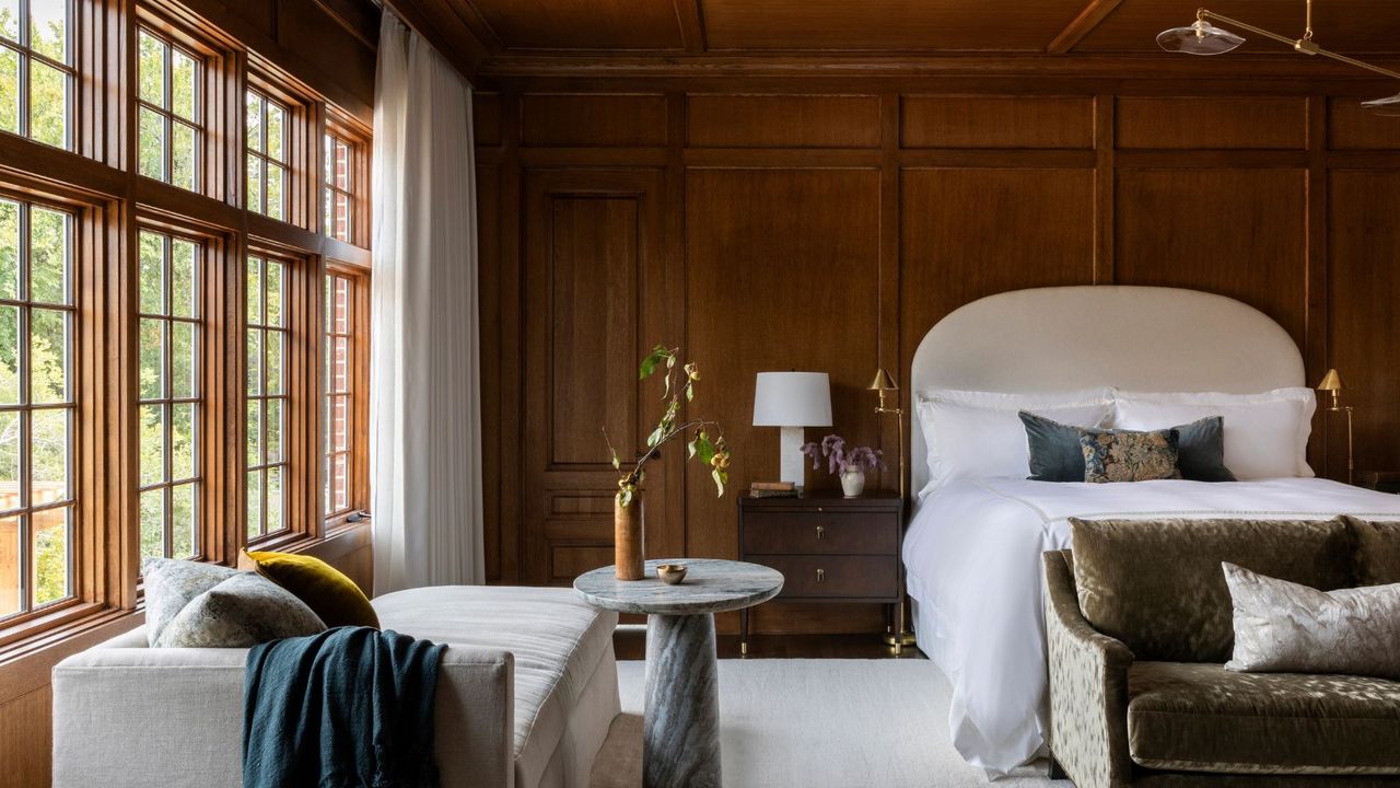 Dark wooden panelled bedroom with cream headboard