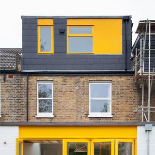 exterior house with yellow framed bifold doors and yellow framed glazing on the loft extension