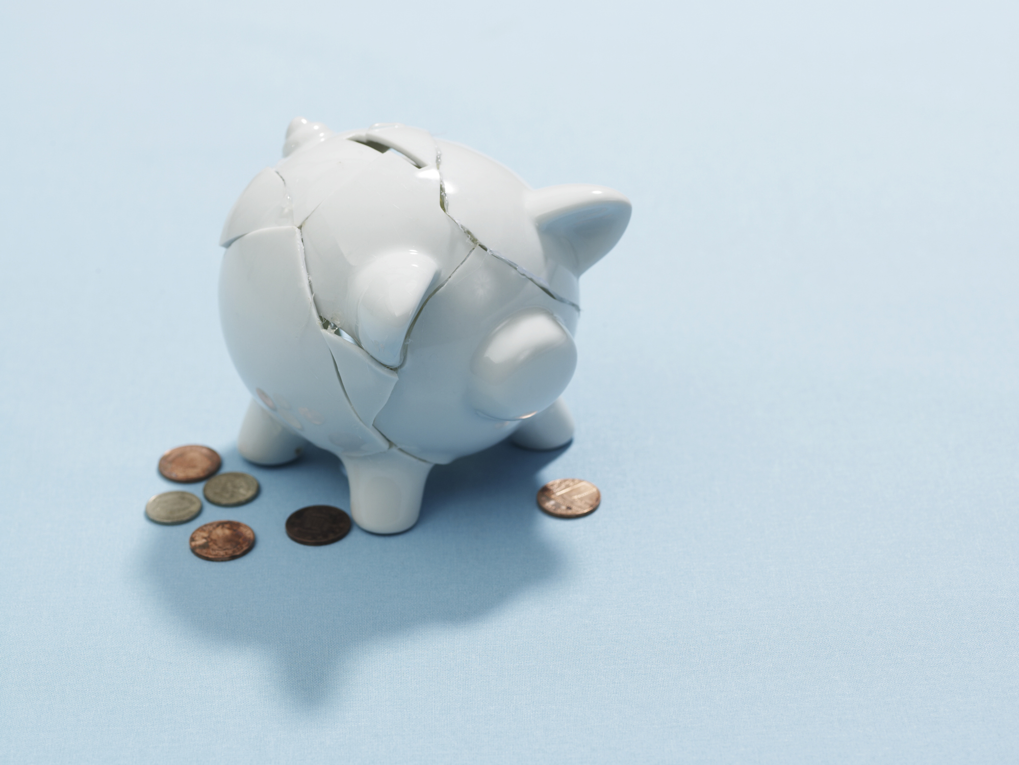 Broken piggy bank with coins next to it.