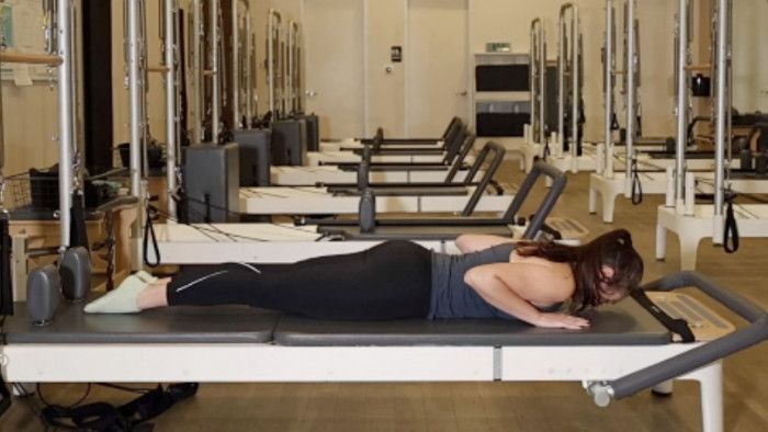 Woman on a Reformer Pilates machine demonstrating an exercise