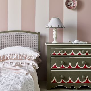 Pink and white stripey bedroom wall with brown and red painted chest of drawers