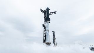 A giant black and silver Starship rocket surrounded by vapor