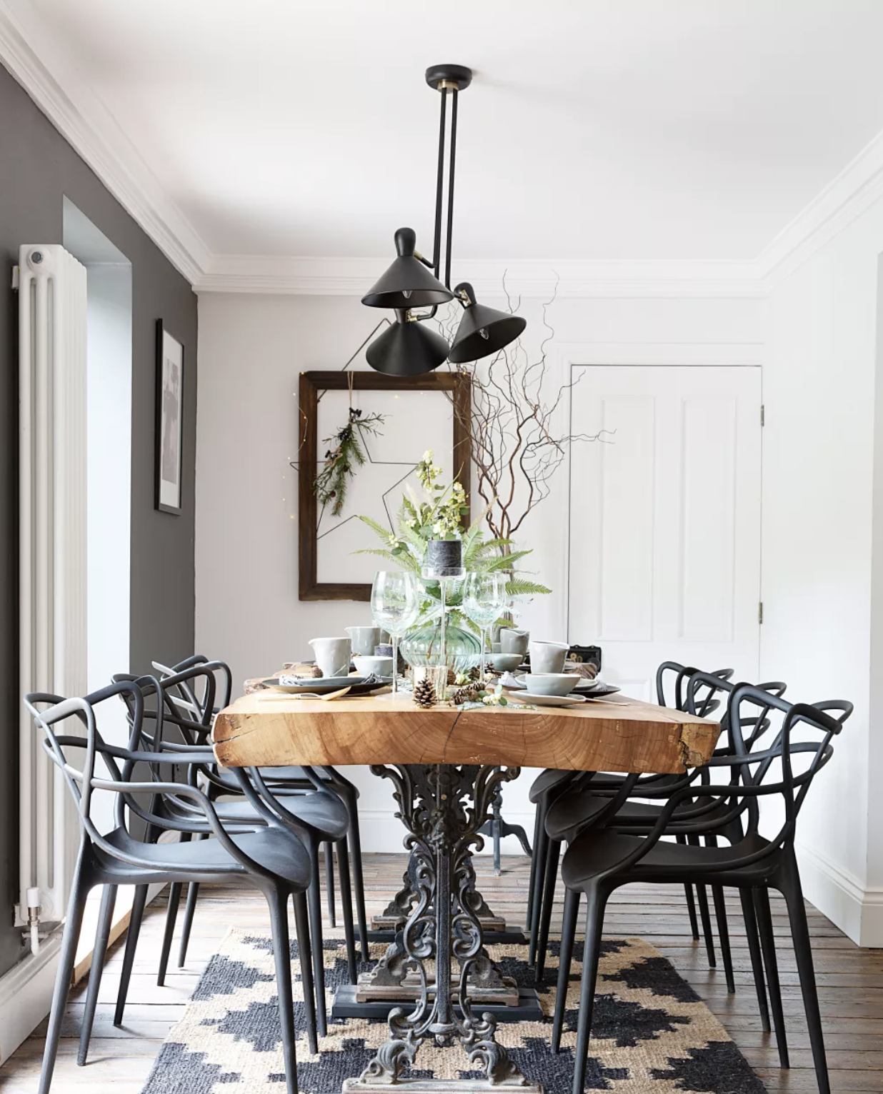 Black and white dining room with wooden table top and green Christmas foliage