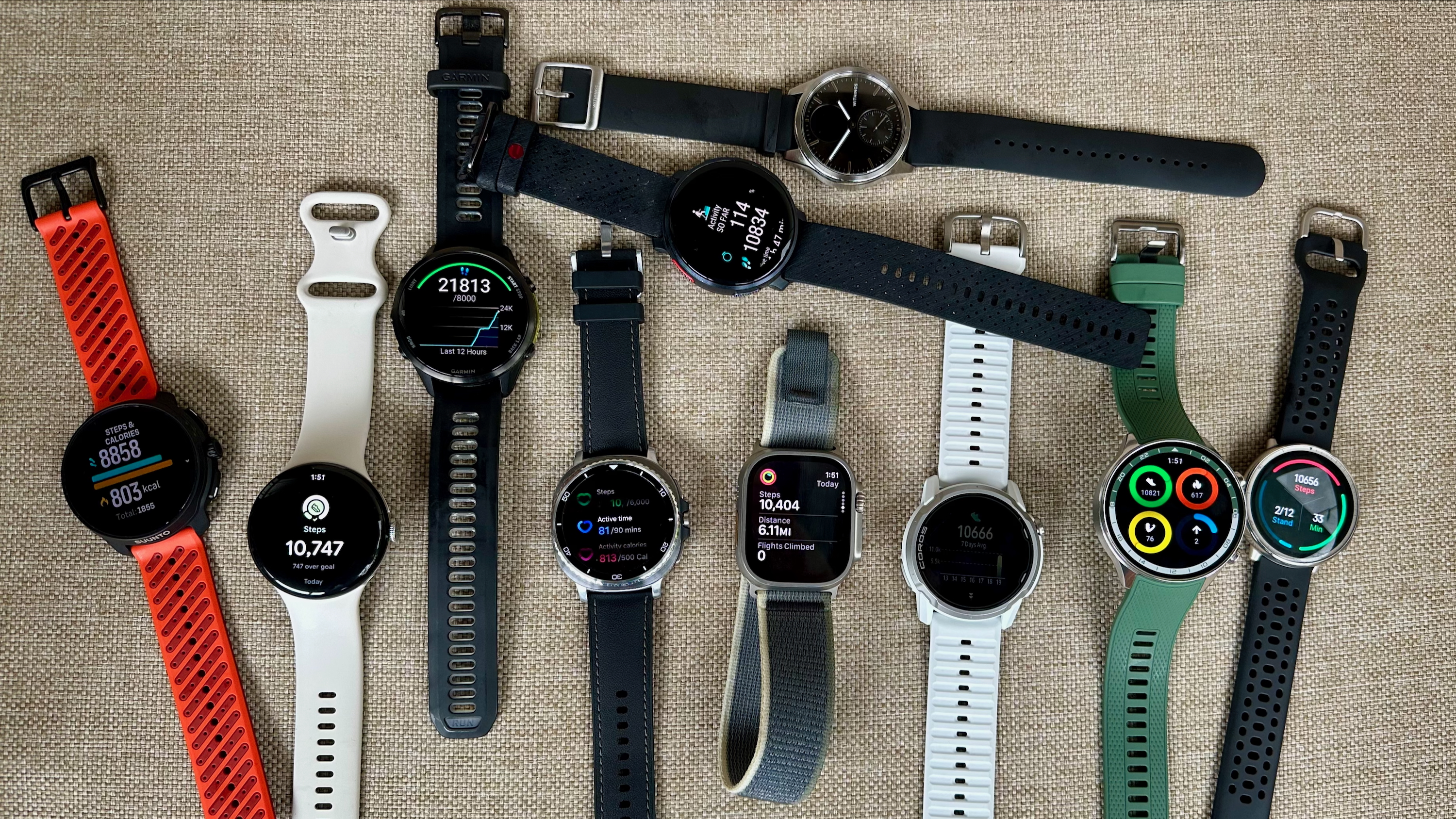 A photo of ten smartwatches sitting on a chair, their displays all showing step-count data.