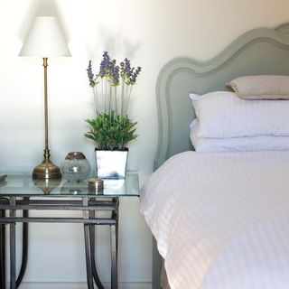 bedroom with bed and white bedding and bedside table with lamp