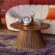 A round coffee table in front of a white curved sofa from Wayfair