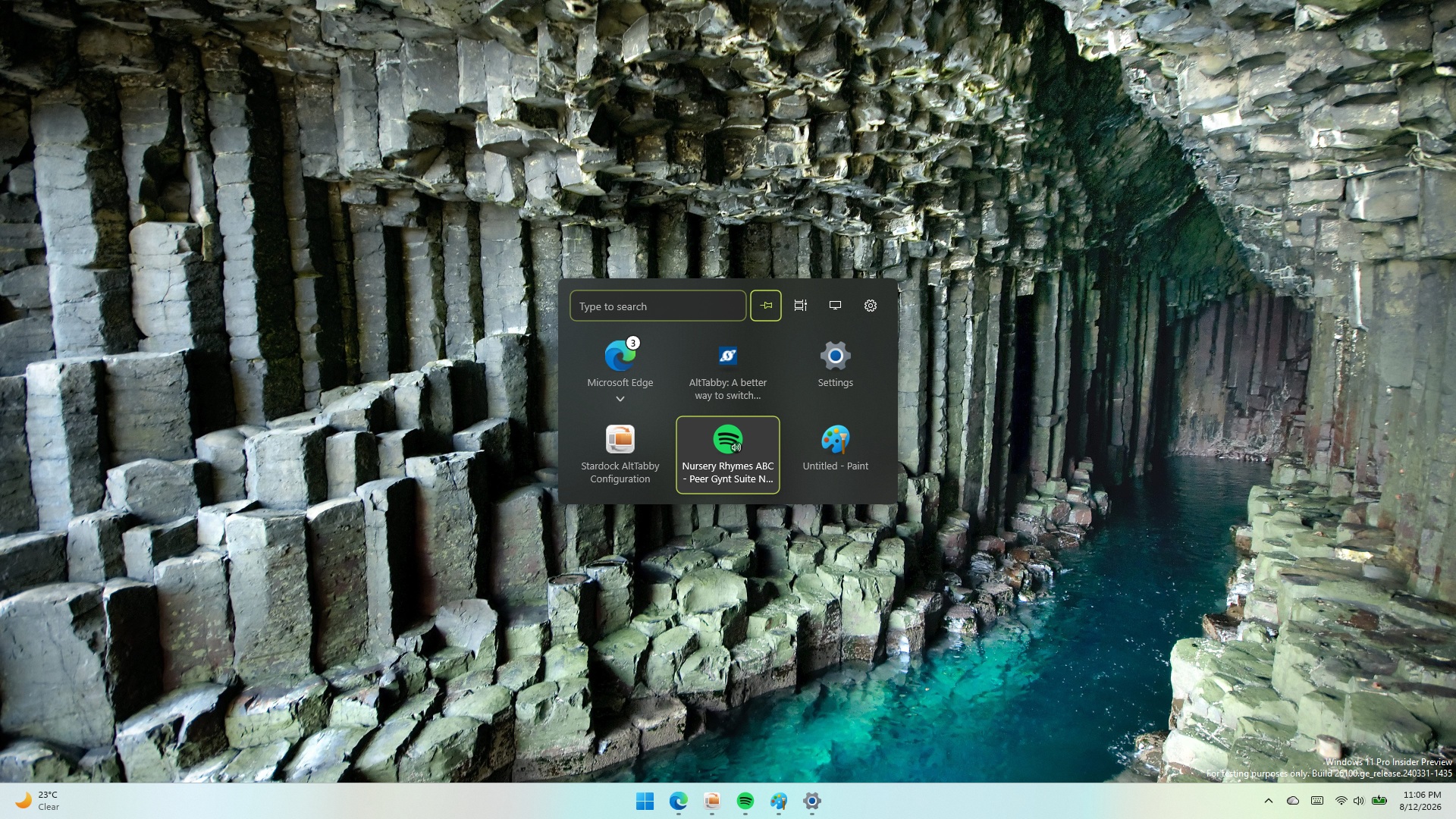 Screenshot of AltTabby running on Windows 11 with a compact, grid-based icon switcher menu centered over a desktop wallpaper of basalt rock columns.