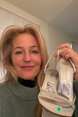 Gillian Anderson holding her shoes ahead of the auction.