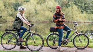 Two women riding bikes down a canal path