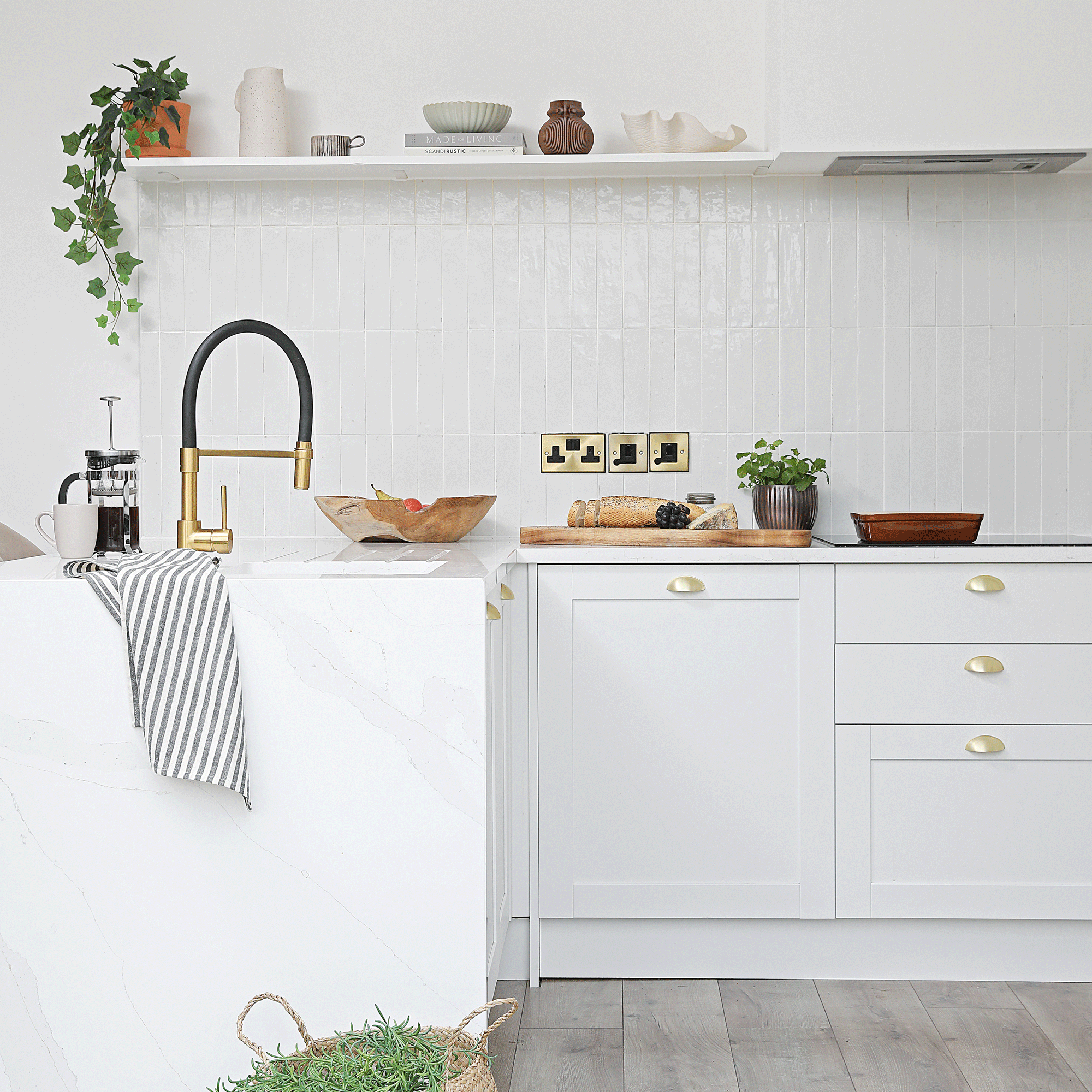 a small white shaker-style kitchen with pale grey wooden flooring and white tiled splashback
