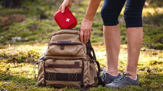 Hiker taking out first aid kit from backpack