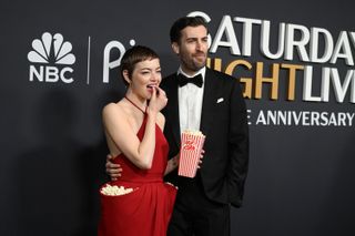 Emma Stone wears a bright red custom Louis Vuitton gown with her pockets filled with popcorn