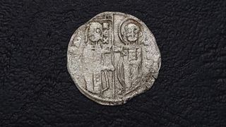 Two kings are depicted on one side of an ancient stamped silver coin.
