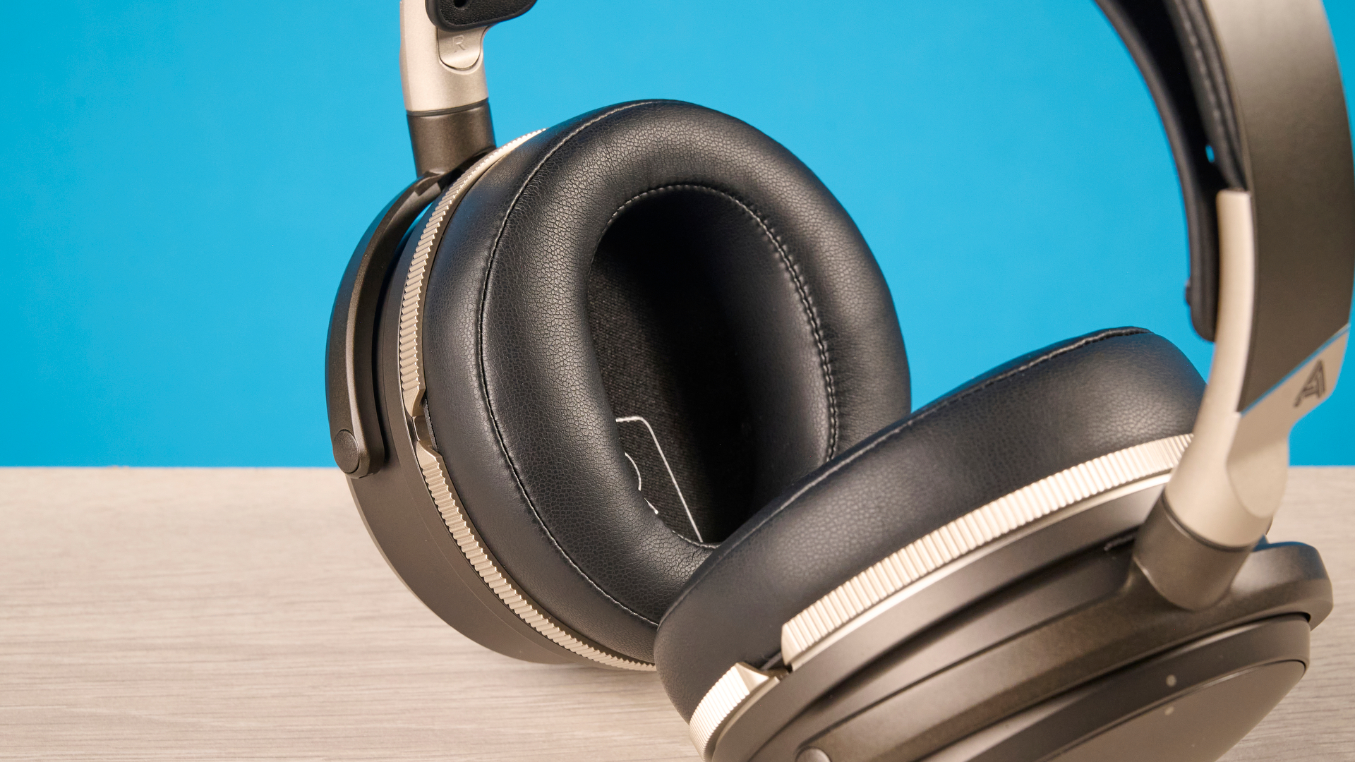 The Audeze Maxwell 2 ANC on a wooden desk with a blue background