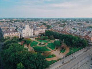 A historic square is captured at dusk, showcasing lush greenery and picturesque buildings absorbed in a soft blue light.