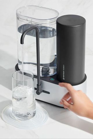Water filter on kitchen countertop, hand touching button