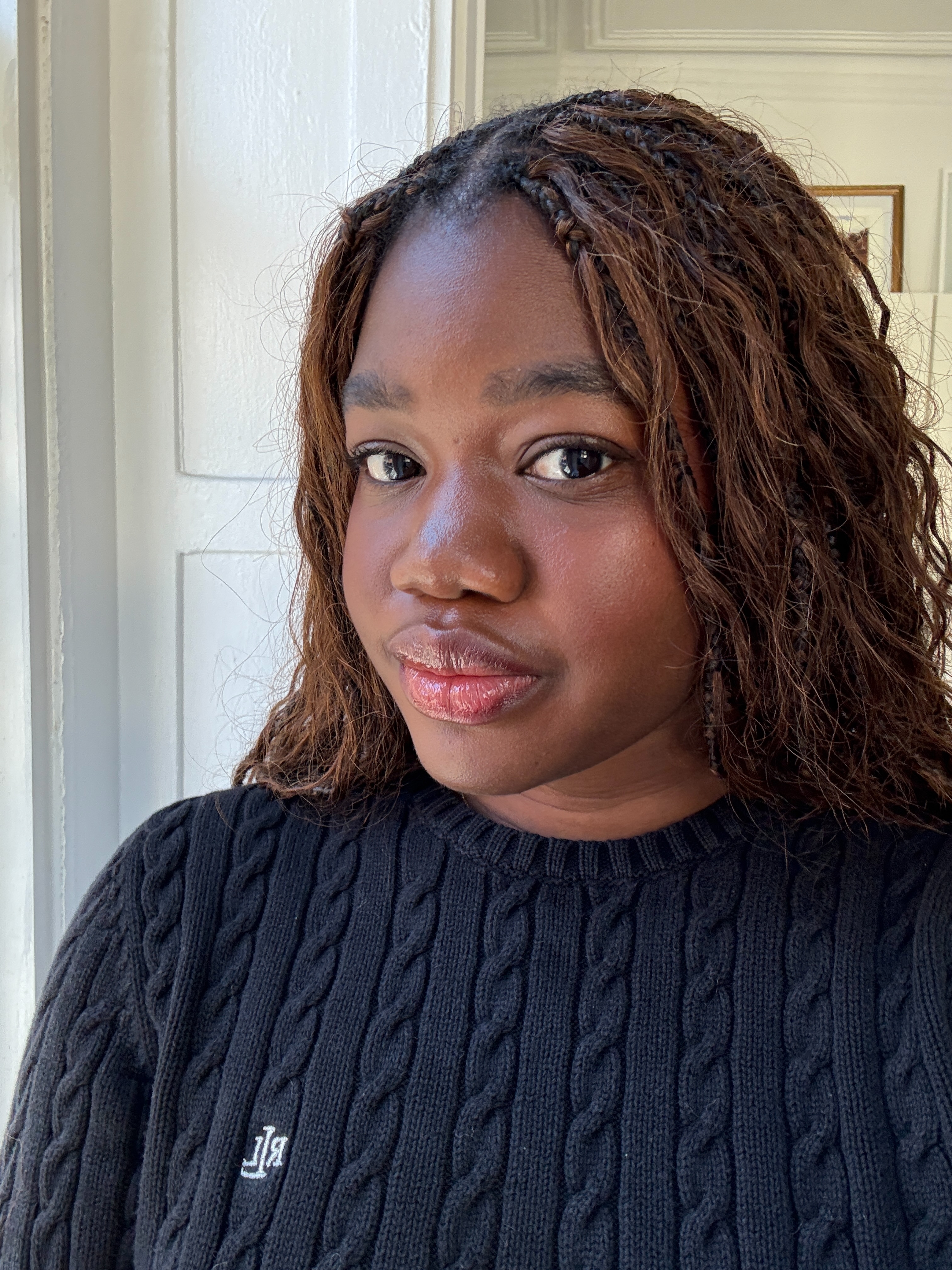 Associate Beauty Editor Maya Thomas with light brown braids wearing a navy Ralph Lauren sweater