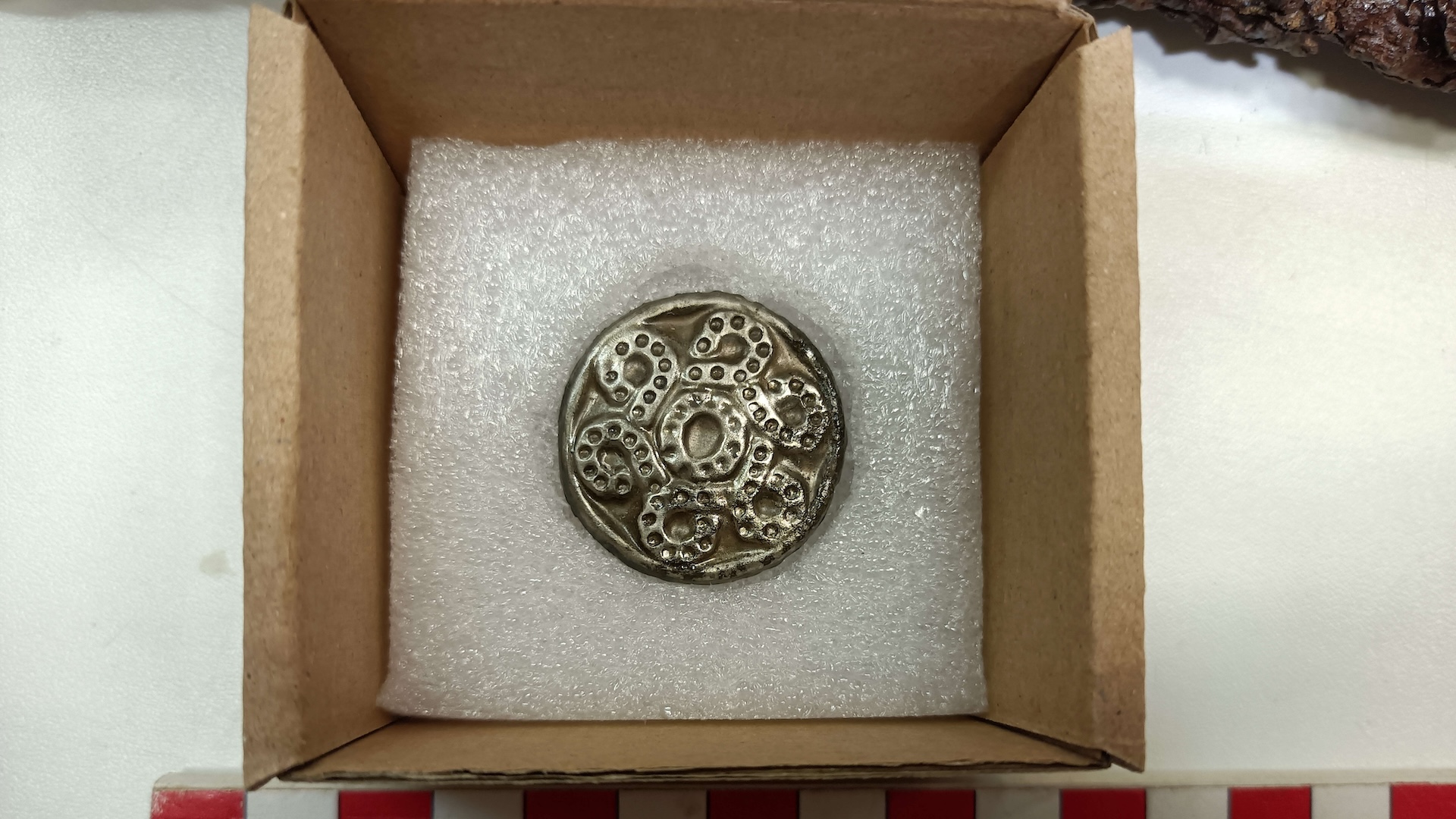 a silver ornamented brooch in a box