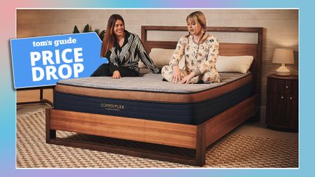 Two women sit on a Brooklyn Bedding Copperflex mattress on a bed frame in a bedroom, smiling and talking about the mattress. To the left, a Tom's Guide Price Drop deals graphic