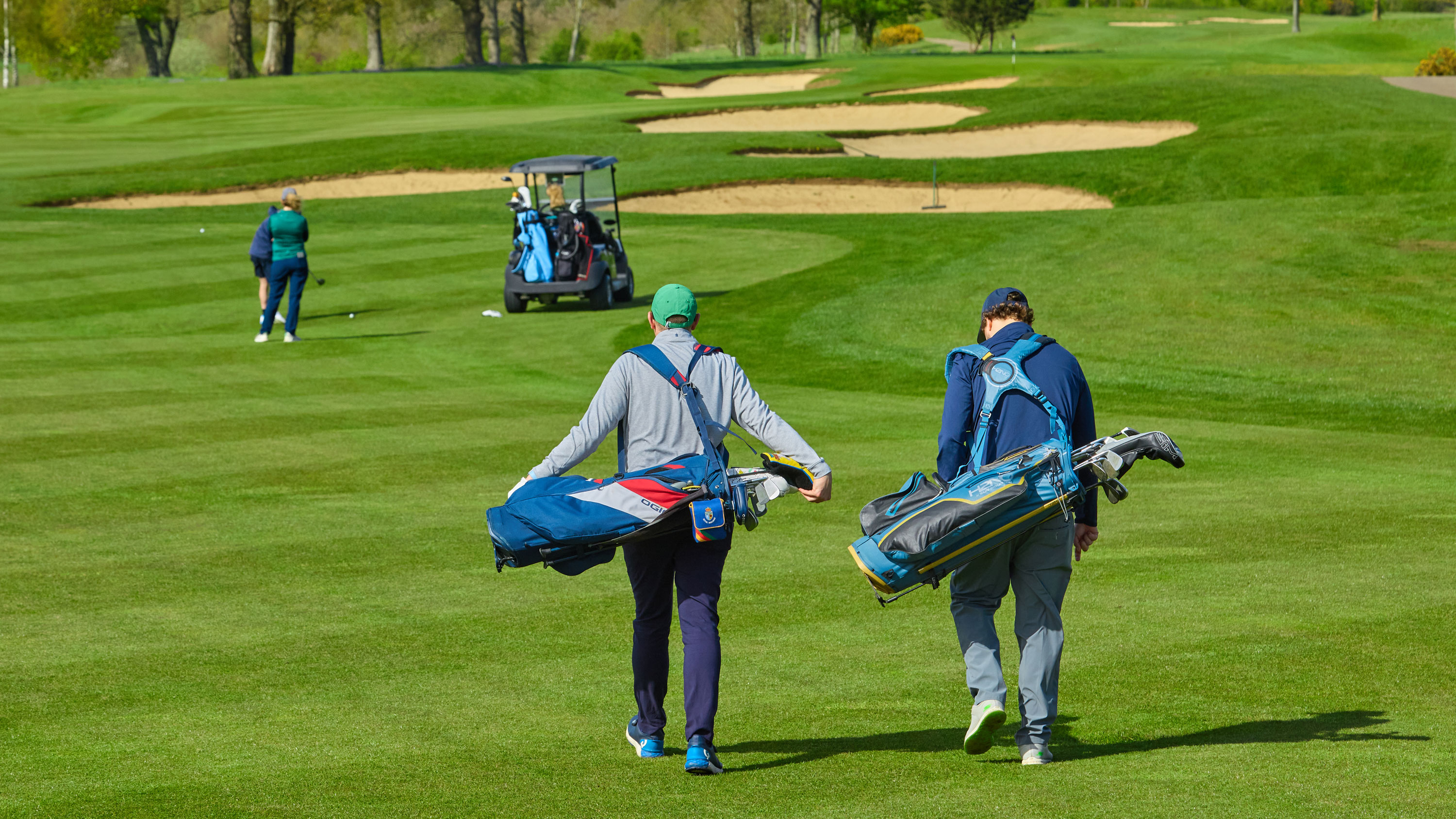 two golfers look ahead to see two other golfers in the fairway