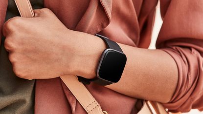 The best Fitbit versa 2 on woman's wrist wearing pink holding bag