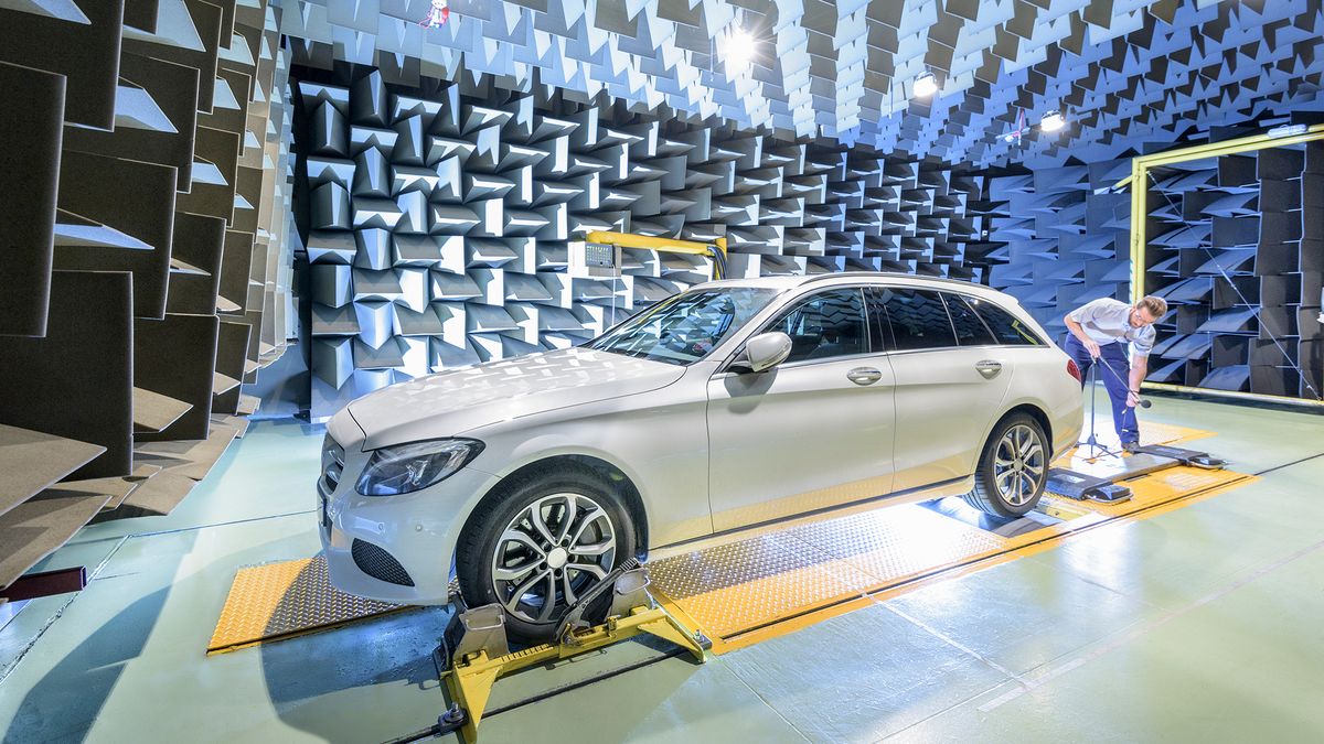 Engineer testing vehicle on rolling road in anechoic chamber