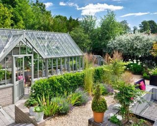 greenhouse in a garden beside a terrace seating area