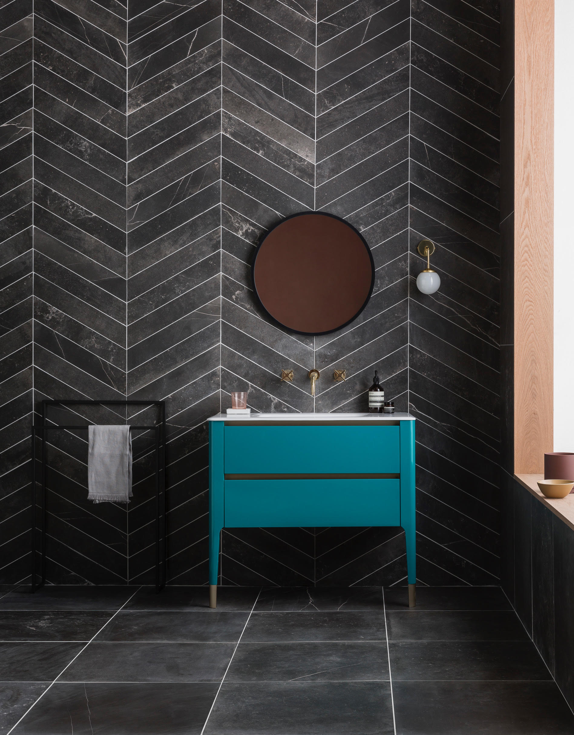 Black bathroom with teal blue cabinet and copper mirror