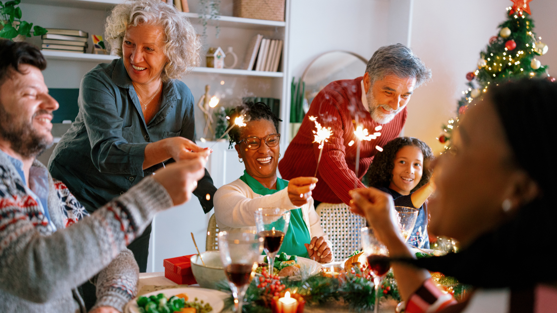 Family sitting around a Christmas table eating dinner with sparklers 