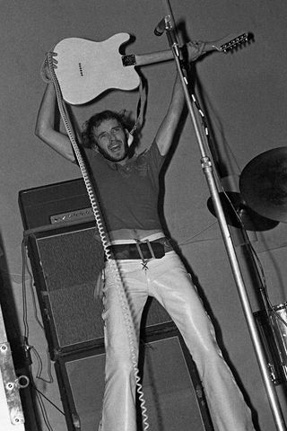 Peter Banks lifting his guitar above his head onstage with Yes