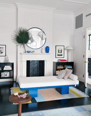 Modern white living room with day bed and fireplace with black painted floorboards