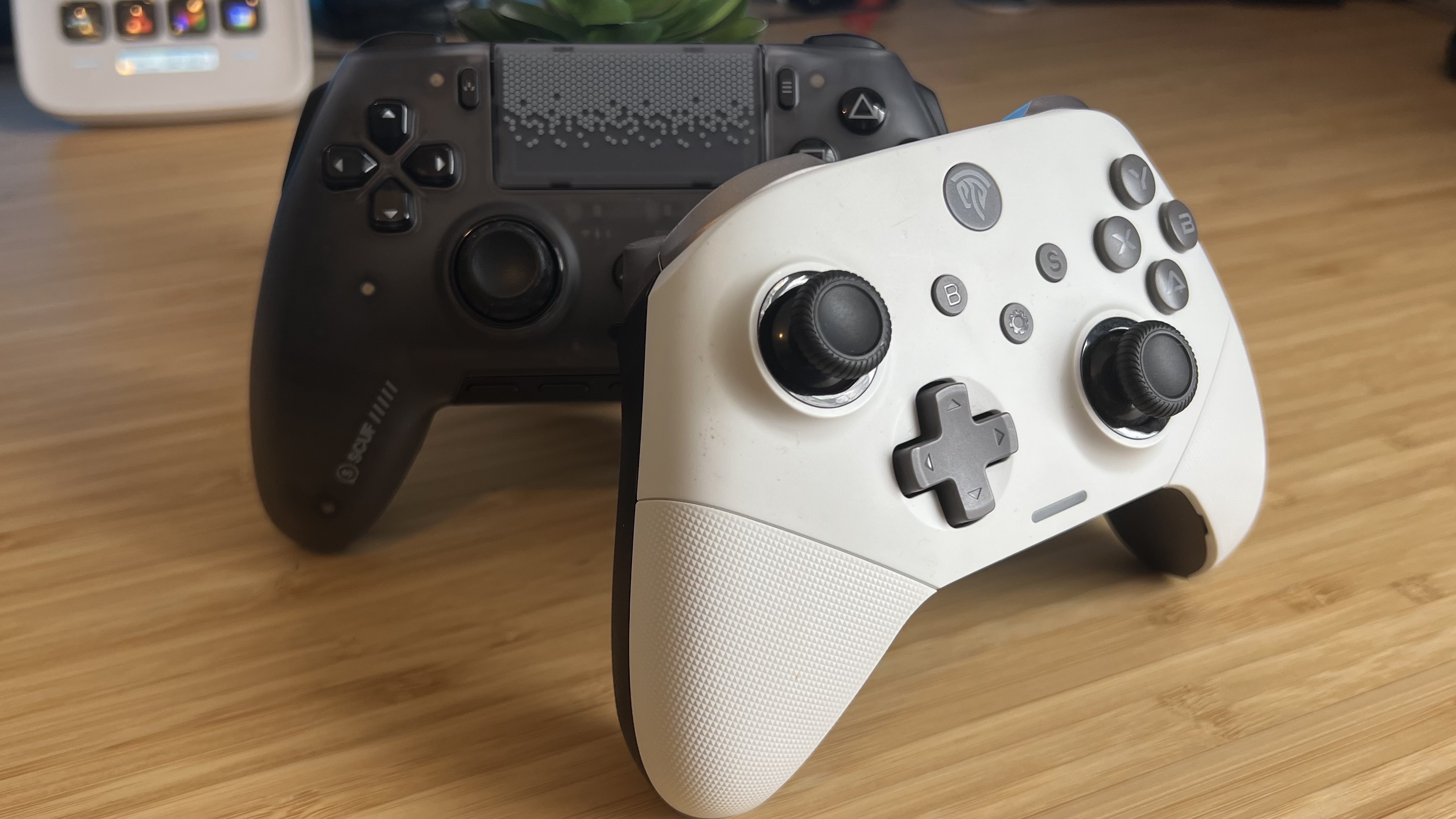 Scuf Omega PS5 controller and EasySMX X10 PC controller on a wooden desk