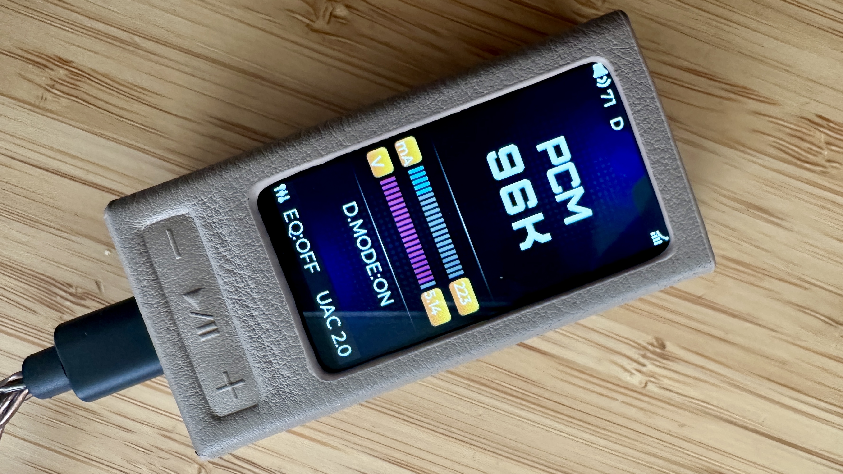 FiiO QX13 headphone amp/DAC in its magnetic protective casing on a wooden surface