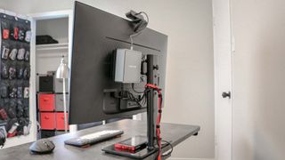 A mini PC mounted behind a monitor to save desk space