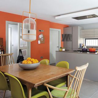 orange kitchen with dining table chairs and fruit bowl