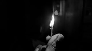 Burning matchstick held in hand