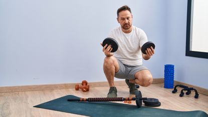 Weight vs reps: Image shows man loading up barbell at home