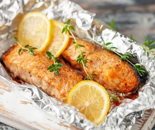 Two salmon filets grilled in foil with lemon and thyme