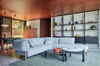 Living room at Il Sereno penthouse with light blue sofa and wall shelving unit in black
