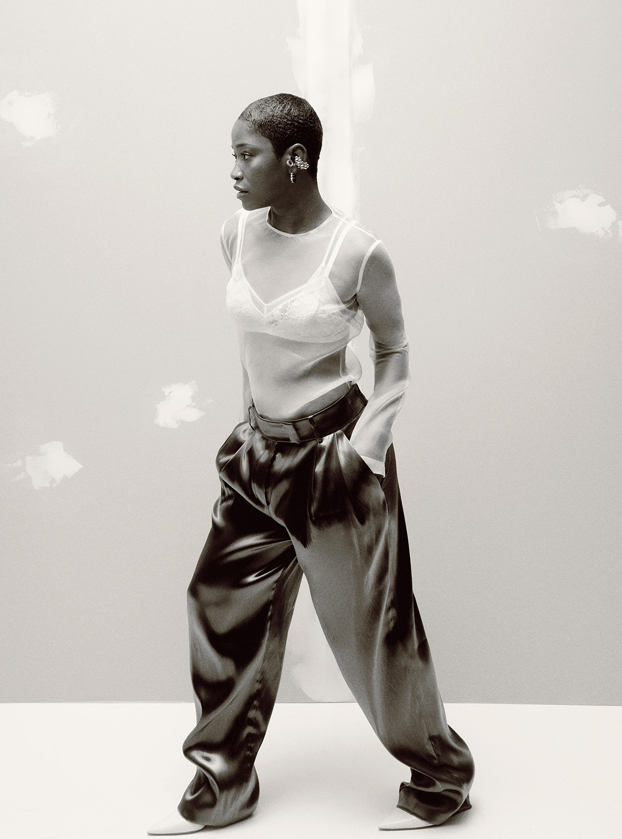 Keke Palmer wearing black patent pants over white heels and a white transparent top over a white bralette
