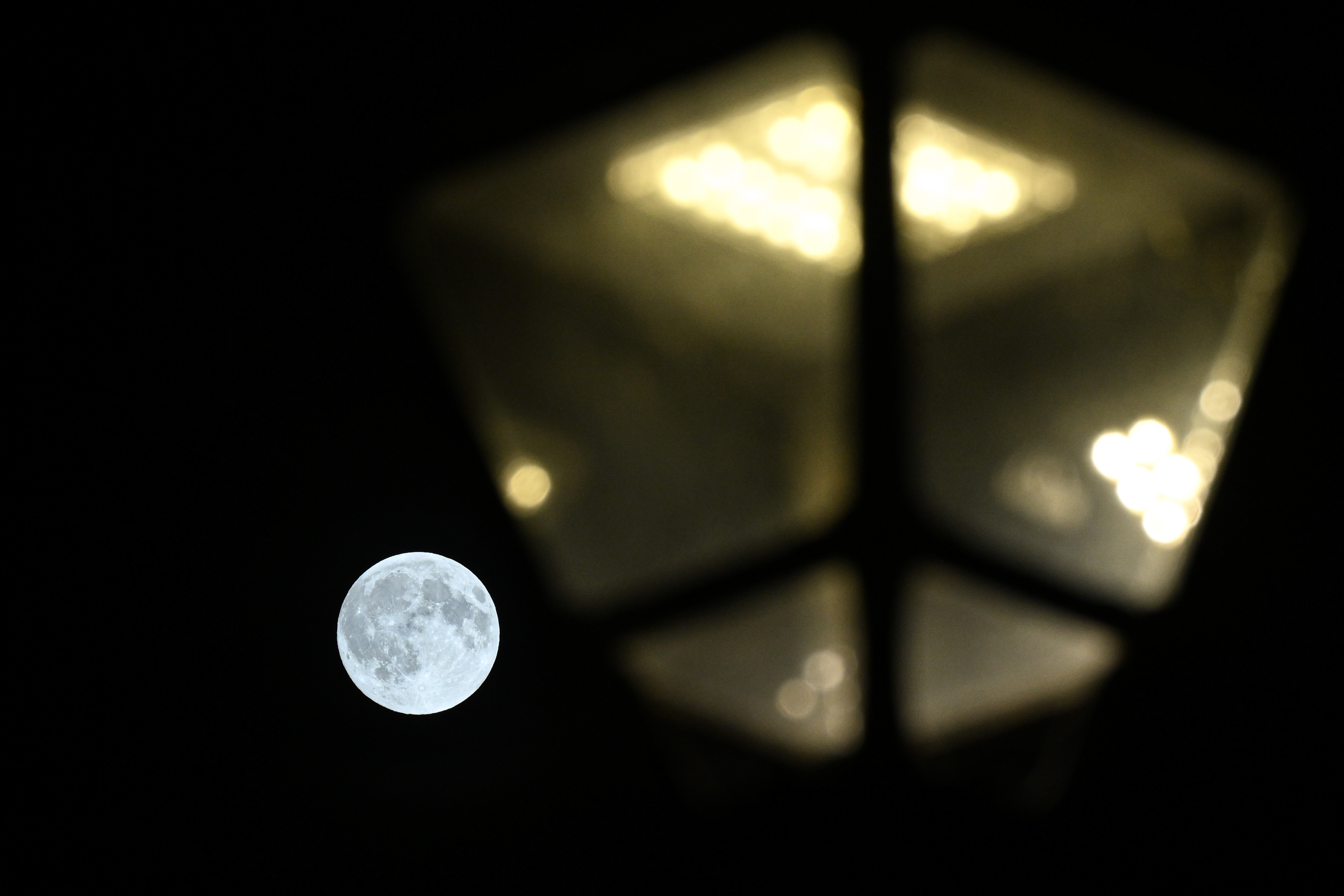 A photograph of the Harvest supermoon behind a street lamp in Manchester, England.