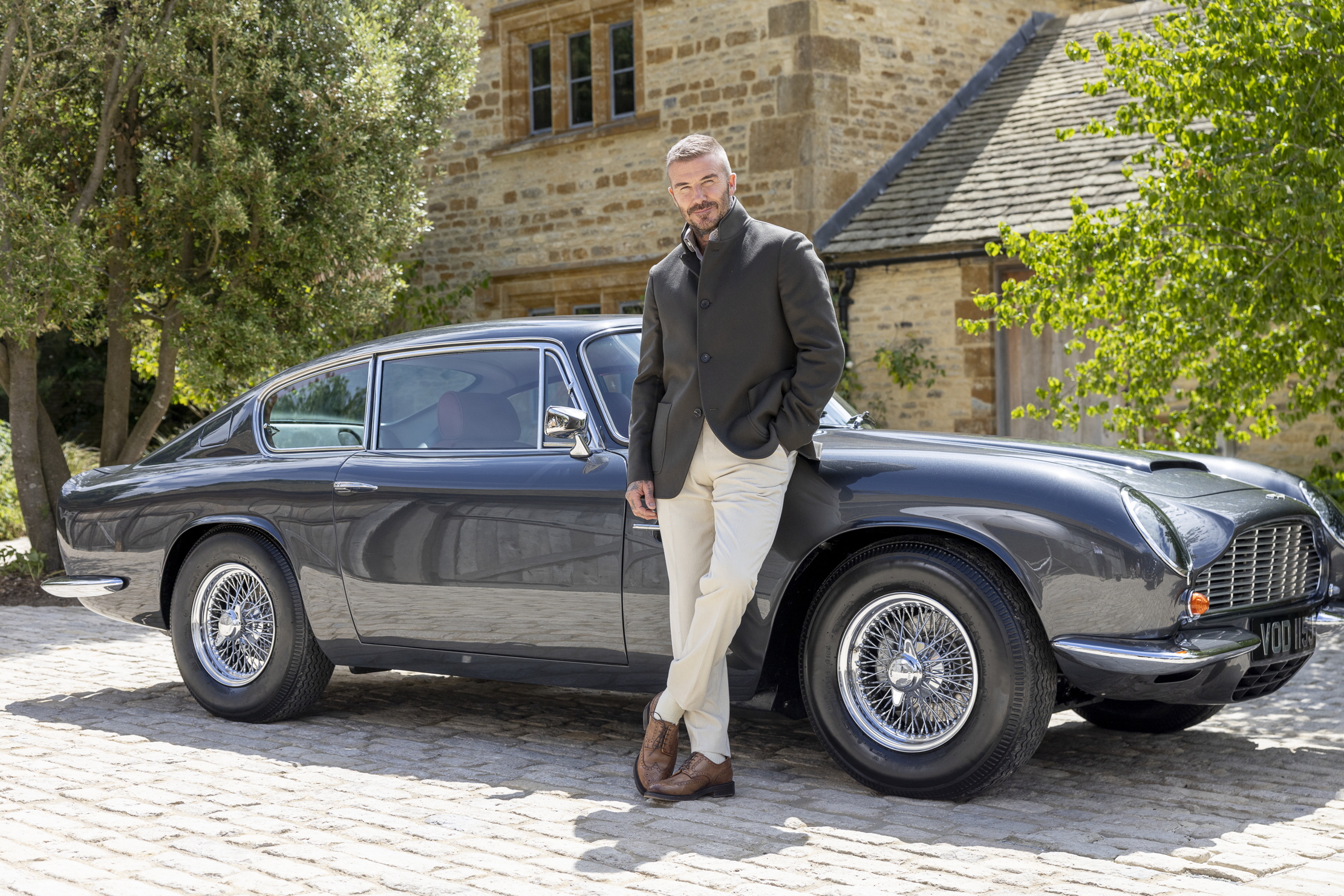 David Beckham stands beside his Aston Martin DB6
