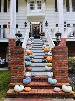grand steps up to house with pumpkins on each side, wreath on door at the top, porch