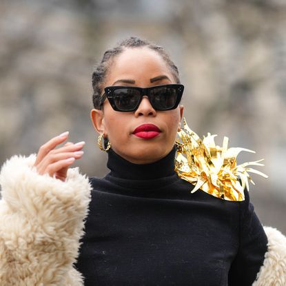 best liquid lipsticks - Ellie Delphine wears black sunglasses, gold earrings, a black turtleneck pullover, a white latte oversized sheep fur long coat, gray denim wide legs pants, outside Stephane Rolland, during Paris Fashion Week - Haute Couture Spring Summer, on January 24, 2023 in Paris, France